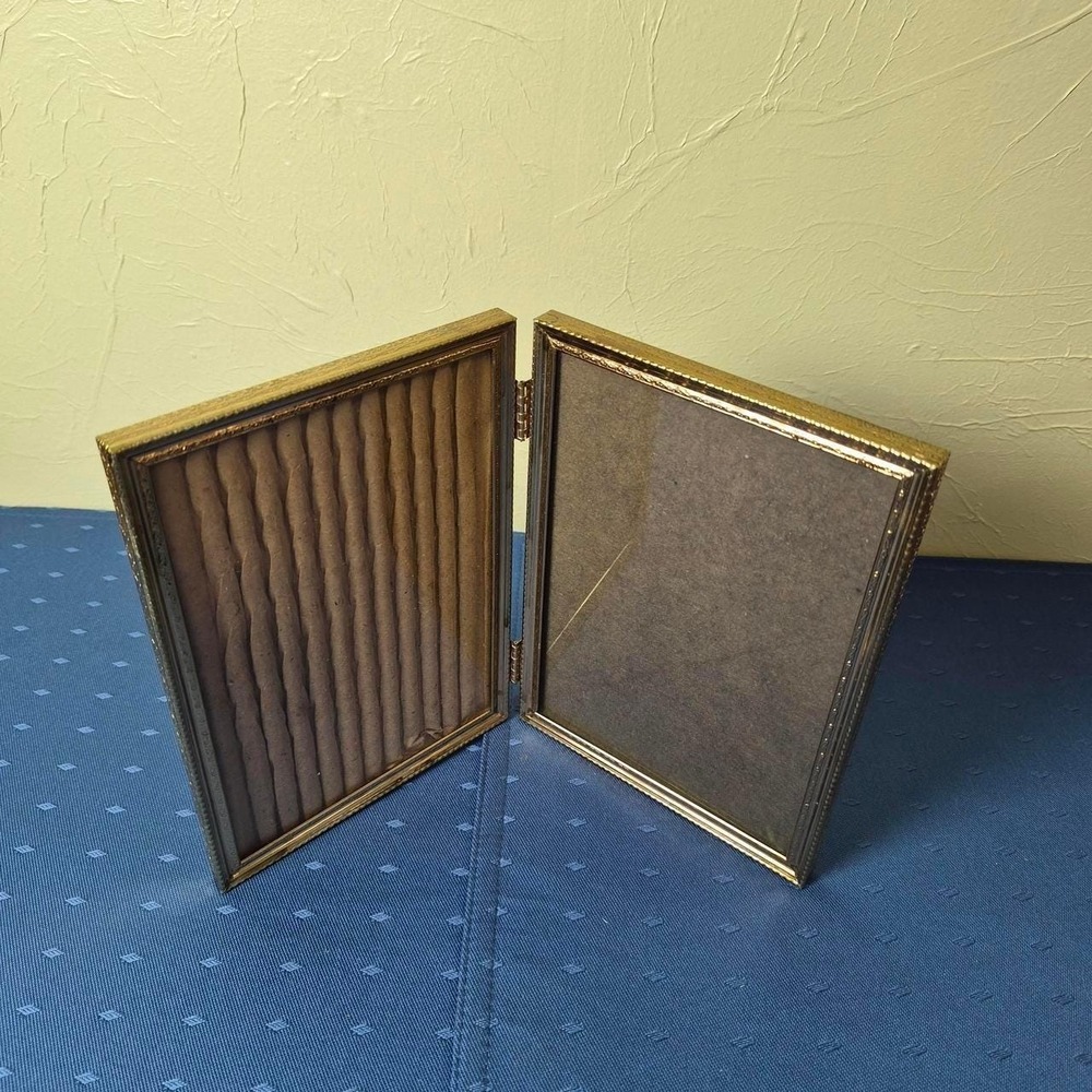Vintage hinged gold picture frame with vertical ridges.